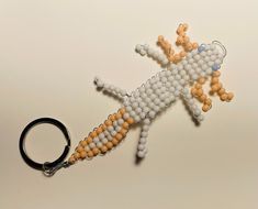 a keychain made out of beads with a gecko on it's side