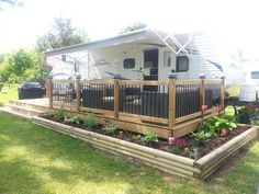 a mobile home sits in the middle of a grassy area with flowers and plants growing on it