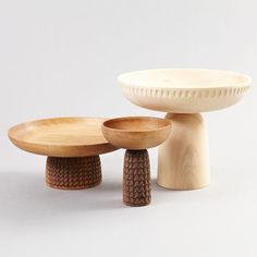 three wooden bowls sitting next to each other on top of a white table with one bowl in the middle