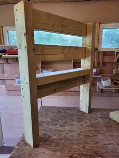 a wooden bunk bed frame in a room with wood flooring and unfinished walls around it