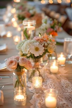 the table is set with candles and flowers in mason jar vases on lace runner