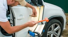 a man opening the door of a white car with an orange handlebar and wrench