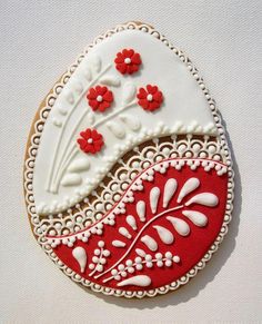 two decorated cookies sitting on top of a white table next to each other with red and white decorations