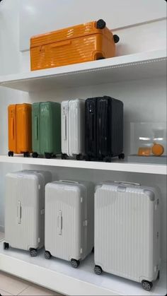 several suitcases are lined up on the shelf in front of each other, all different colors and sizes