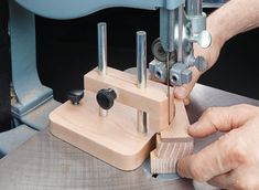 a person using a sewing machine to sew something on the wooden block with holes in it