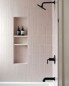 a white bath tub sitting next to a shelf filled with bottles and vases on top of it