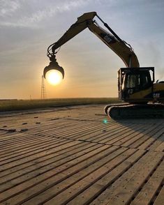 an excavator is setting on the ground at sunset