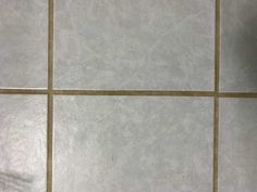 an orange cat sitting on the floor in front of a tiled wall with white tiles