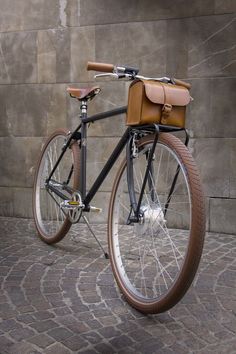 a bicycle parked on the side of a building with a bag strapped to it's seat