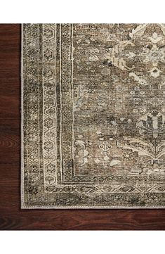 an antique rug on a wooden floor with dark brown wood floors and white, beige and green colors