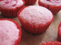 some red cupcakes are sitting on a wooden table and ready to be eaten