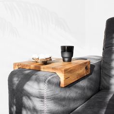 a wooden tray sitting on top of a gray couch next to a cup and saucer