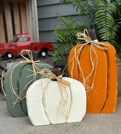 three pumpkins with twine tied to them sitting in front of a house