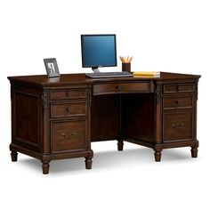 a desk with a computer on top of it and a laptop in the bottom drawer