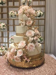 a three tiered wedding cake with pink and white flowers on the top, sitting on a table