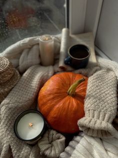 an orange pumpkin sitting on top of a window sill next to some yarn and candles