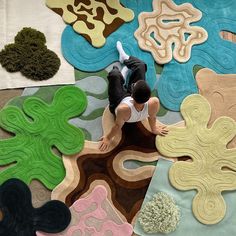 a person sitting on top of a rug covered in different colored shapes and sizes,