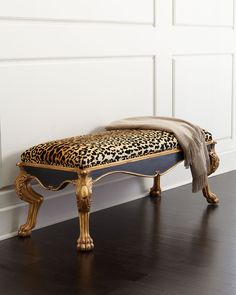 a leopard print bench sitting on top of a hard wood floor next to a white wall