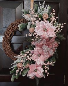 a wreath with pink flowers and greenery hanging on the front door for holiday decor