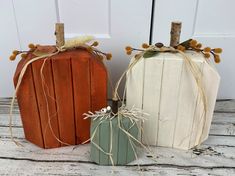 two small pumpkins sitting next to each other on top of a wooden flooring