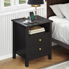 a night stand with a phone on it next to a bed and nightstand in a bedroom