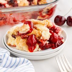 a white plate topped with cherry cobbler next to a fork