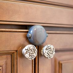 two knobs on the side of a wooden cabinet with an ornate design and metal handles