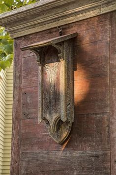 an old wooden building with a clock on it's side and a tree in the background