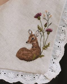 a close up of a piece of cloth with embroidered animals on it and flowers in the background