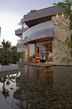 a house with a pool in front of it that is surrounded by trees and plants