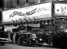 an old black and white photo of people standing in front of a theater