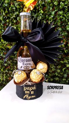 a bottle of liquor sitting on top of a table next to some cookies and flowers