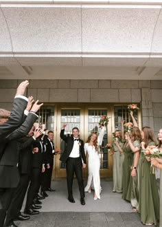 a group of people that are standing in front of a door with their arms in the air