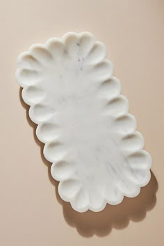 a white plate sitting on top of a table next to a brown wall with a shadow