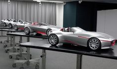 several cars are lined up on display in a room with black walls and white curtains