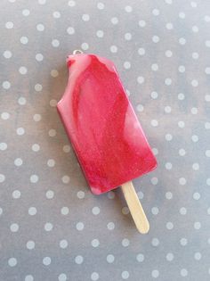 a popsicle with pink icing sitting on top of a polka dot tablecloth