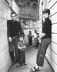 black and white photograph of people standing on the side of a building next to each other