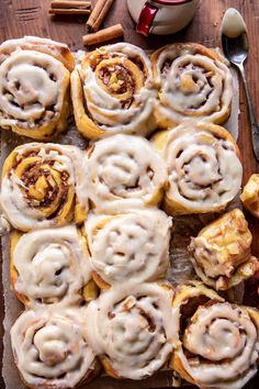 cinnamon rolls with icing sitting on top of a cutting board