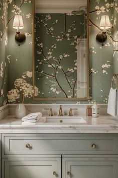 a bathroom with green walls and floral wallpaper on the vanity, along with a gold framed mirror