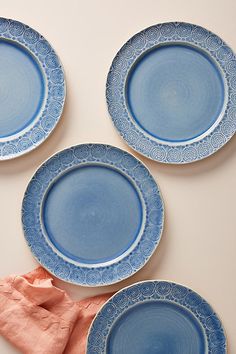 four blue plates sitting on top of a white table