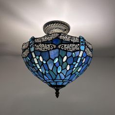 a ceiling light with a blue glass shade hanging from it's center point and dragonflys on the top