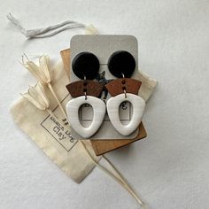 a pair of wooden earrings sitting on top of a piece of fabric next to a bag