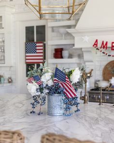 an american flag arrangement in a silver vase on a marble countertop with blue berries and white carnations