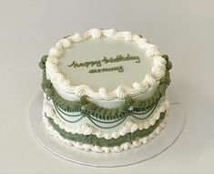 a white and green birthday cake sitting on top of a glass plate with the words happy birthday army written on it