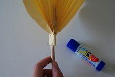 a hand holding a yellow fan next to a tube of toothpaste