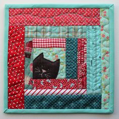 a close up of a patchwork quilt with a cat on the front and side