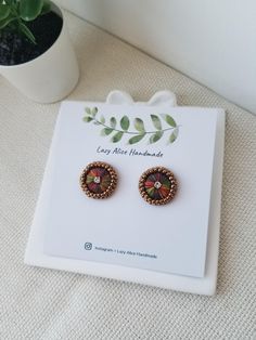 a pair of earrings sitting on top of a white table next to a potted plant