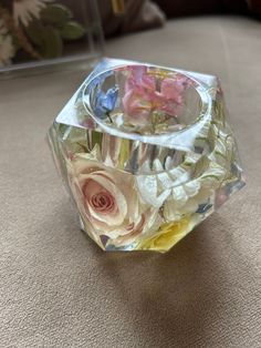 a clear glass vase with flowers in it sitting on a table next to a pillow