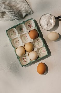 eggs and flour on a tray next to a measuring spoon