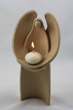 a small candle holder with an angel's wing and a lit candle in it